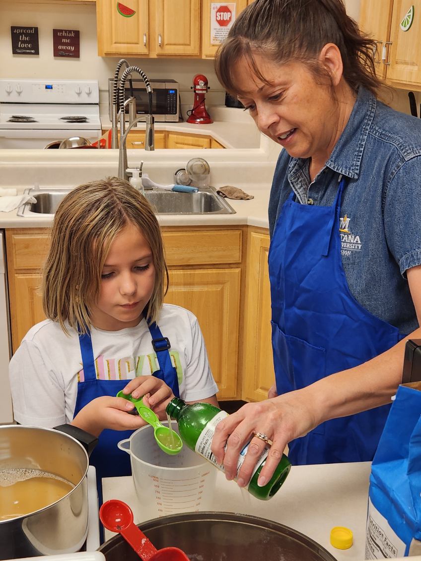 Chouteau County FCS Extension agent Janell Barber teaches a young 4-Her how to measure liquids.